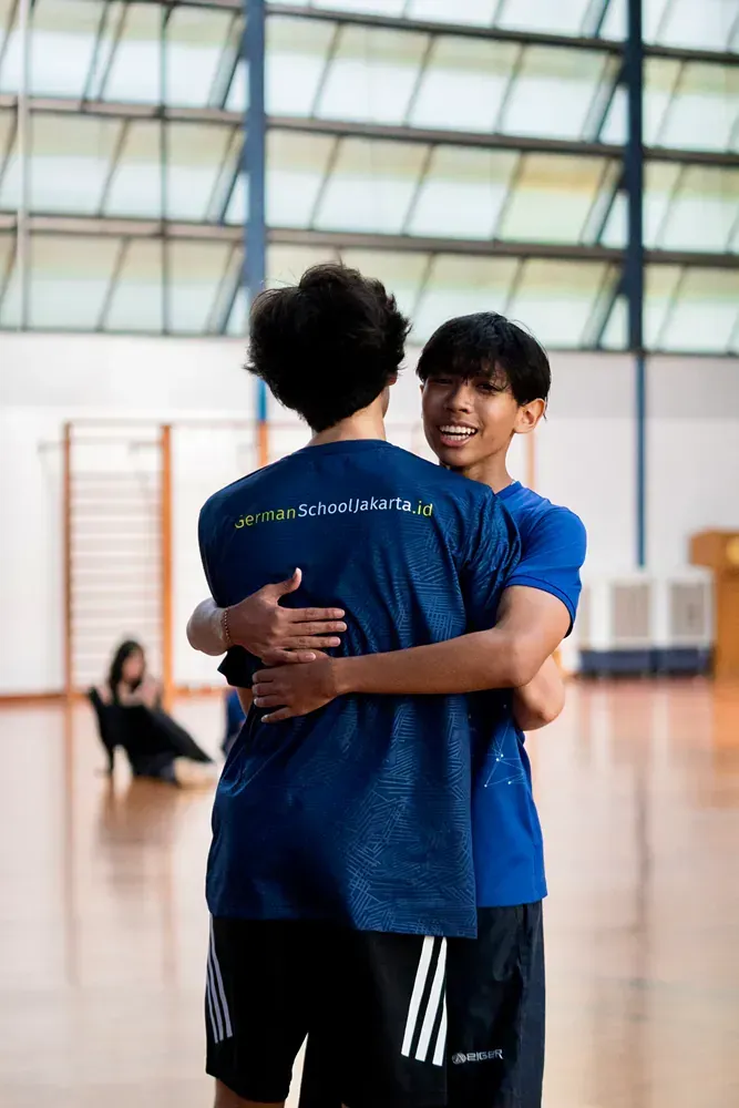 Two young men are hugging each other in a gym.