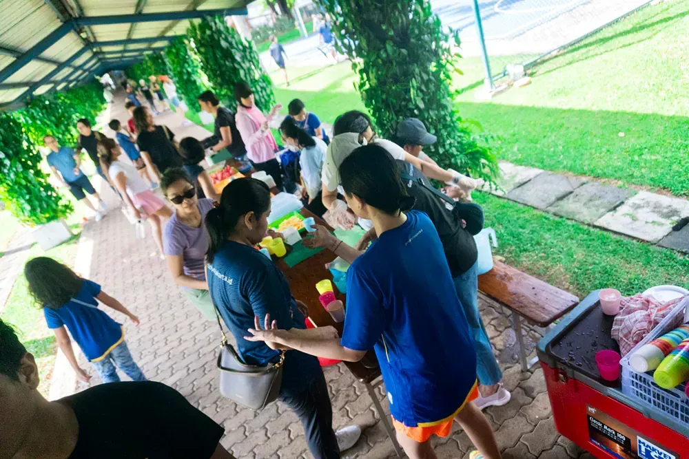 A group of people are standing around a table in a park.
