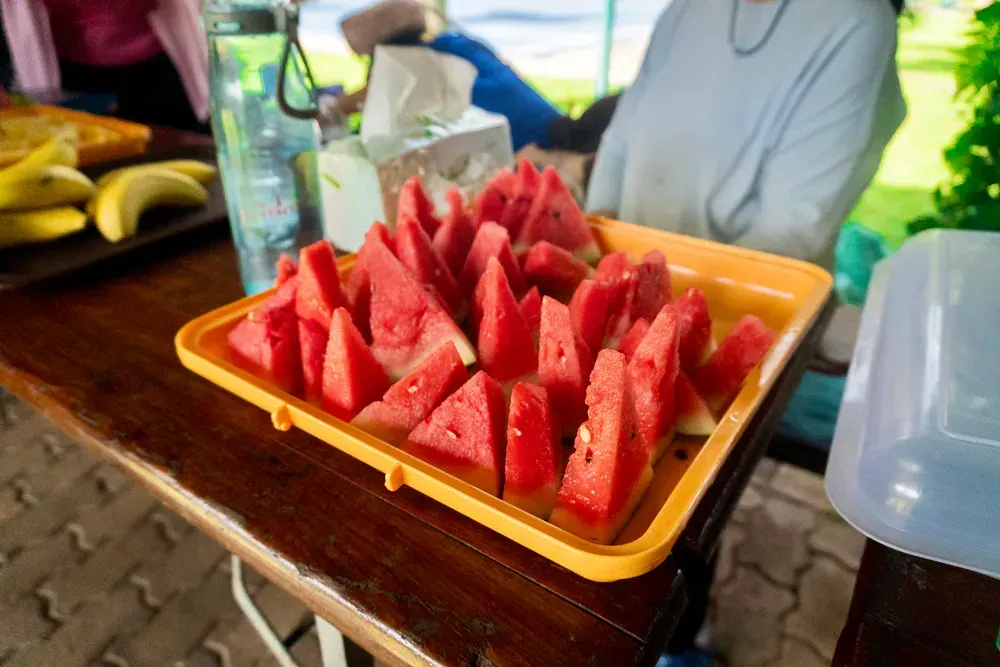 A tray of watermelon slices on a wooden table.