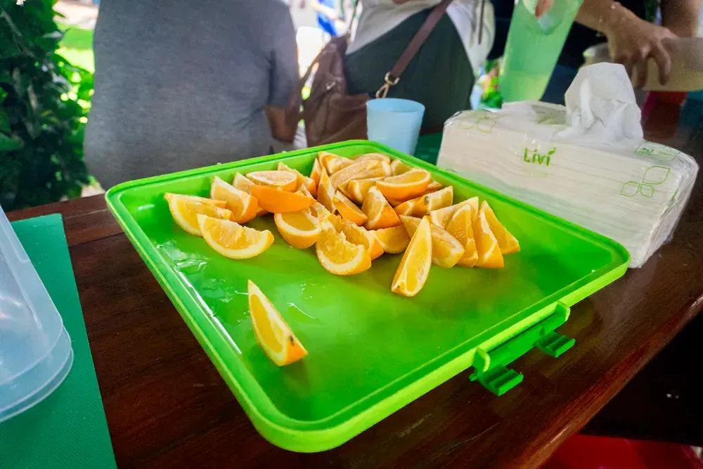 A green tray filled with sliced oranges on a table.