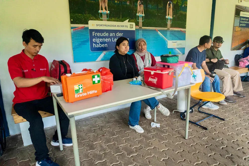A group of people are sitting around a table with a first aid kit on it.