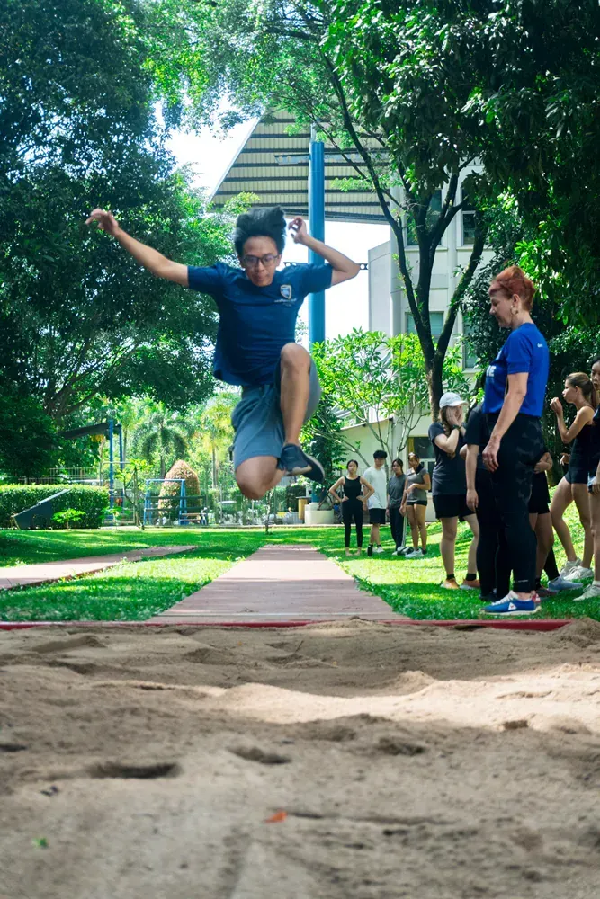 A man is jumping in the air while a group of people watch.