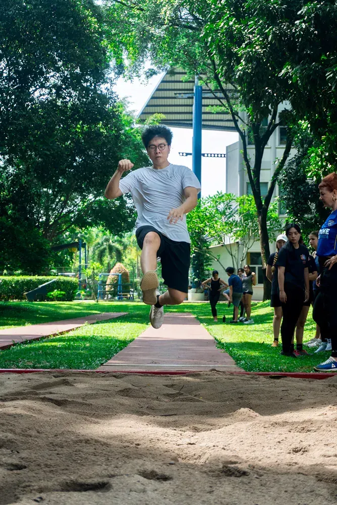 A young man is jumping in the air while a group of people watch.