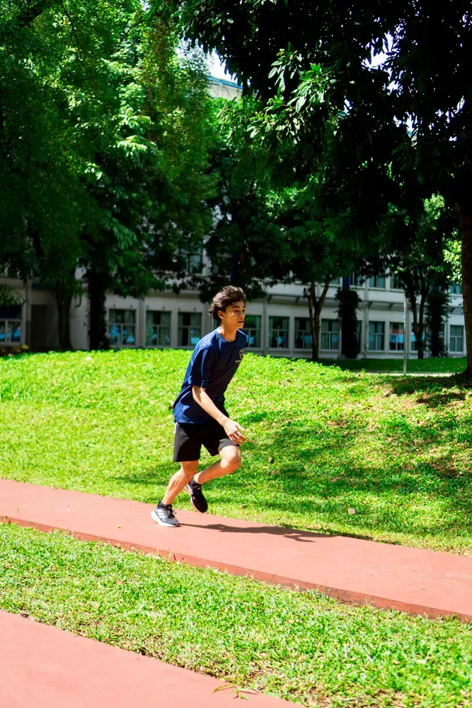 A young boy is running on a track in a park.