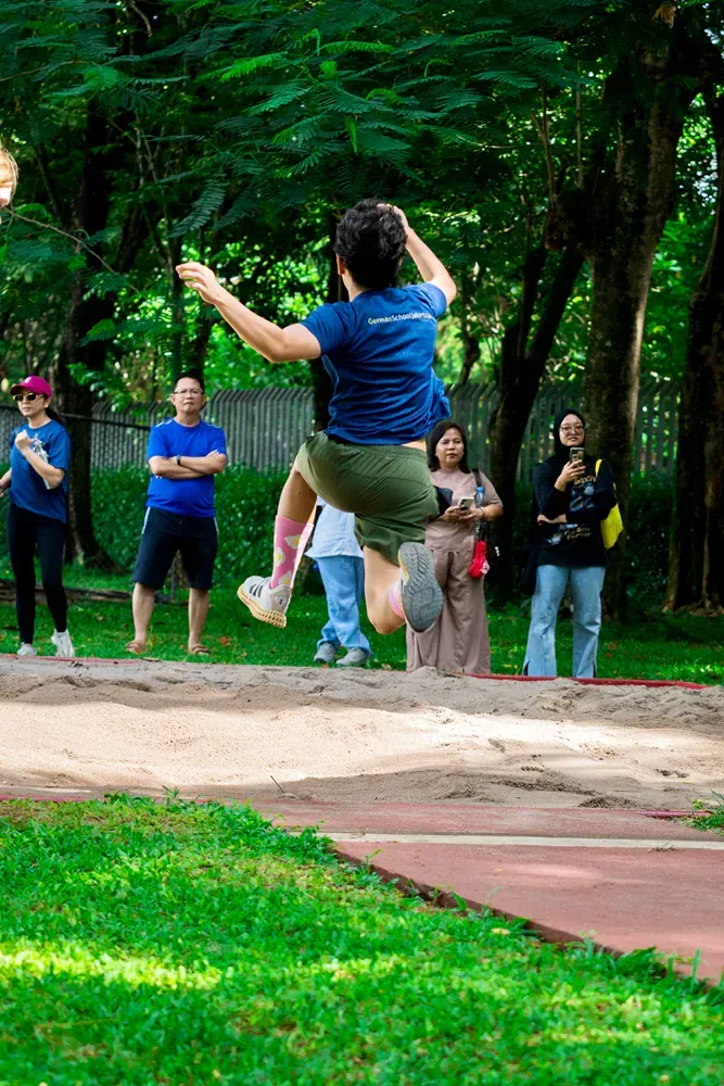 A man is jumping in the air while a group of people watch.
