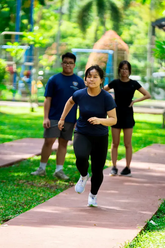 A group of people are running on a path in a park.