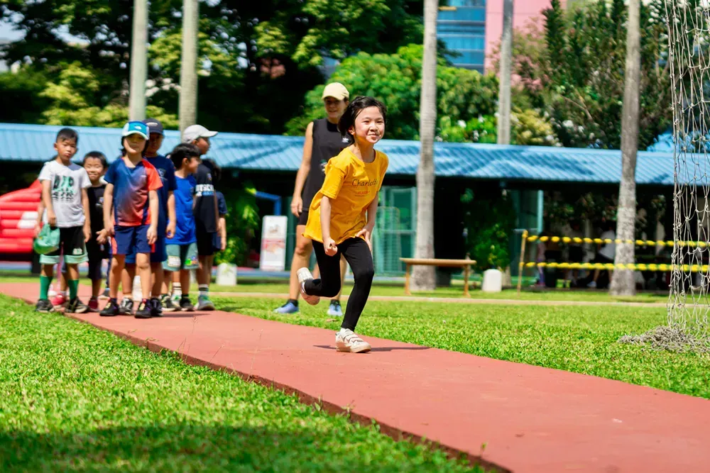 A group of children are running on a track in a park.