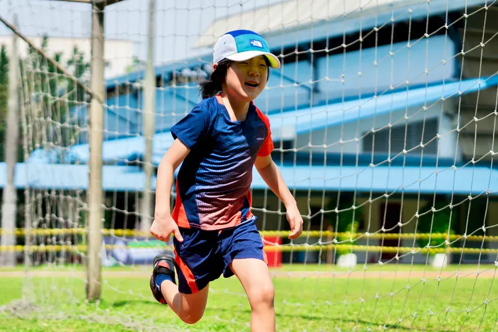 A young boy is running towards a soccer goal.
