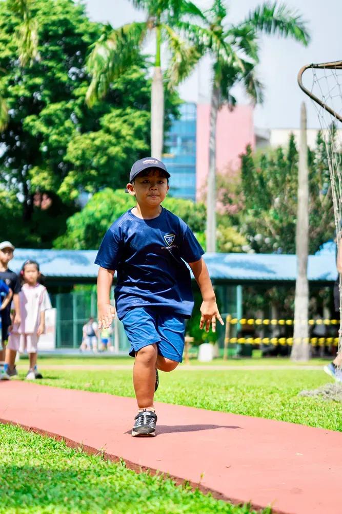 A young boy is running on a track in a park.