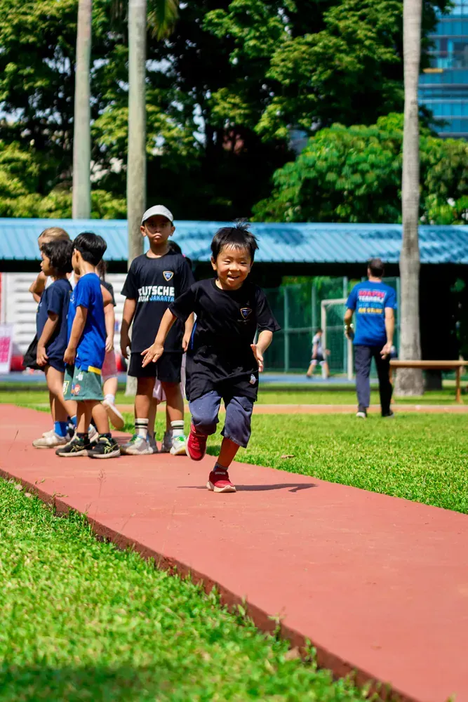 A group of children are running on a track in a park.