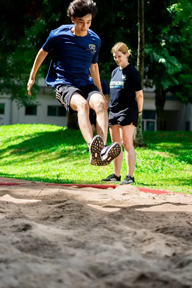 A boy is jumping in the air while a girl watches.
