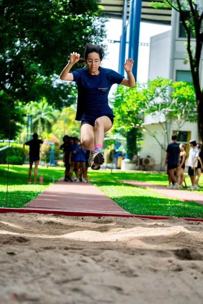 A woman in a blue shirt is jumping in the air