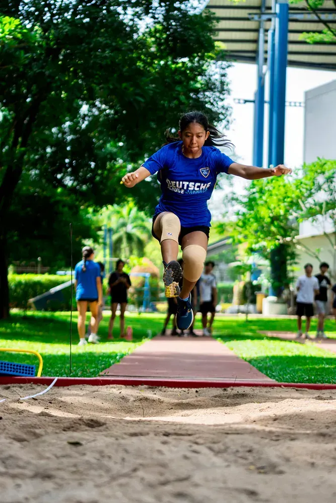 A woman is jumping in the air while wearing a blue shirt.