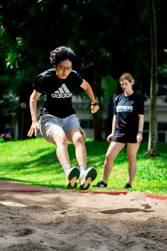 A man is jumping in the air while a woman watches.
