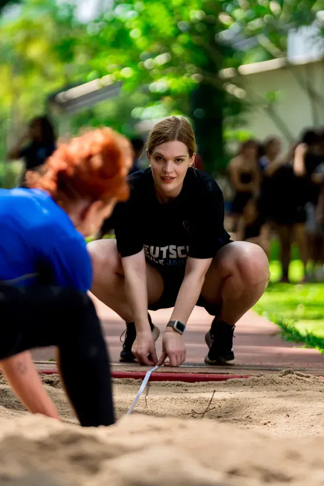 A woman is measuring another woman 's feet in the sand.