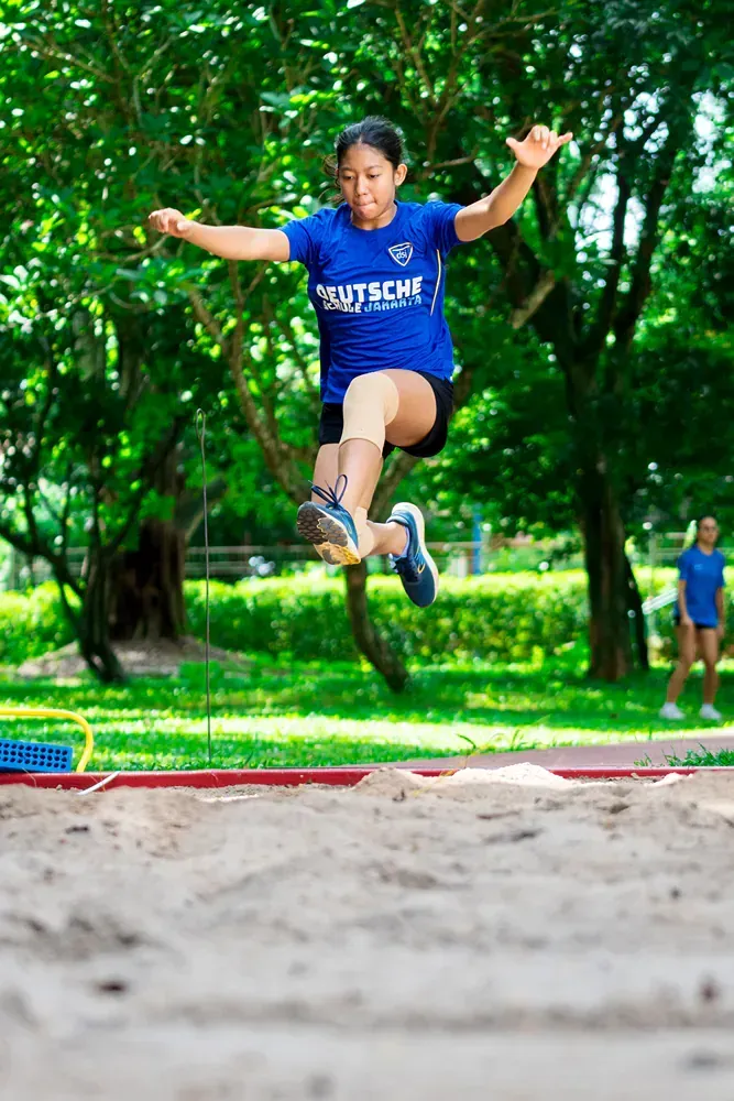 A woman is jumping in the air while wearing a blue shirt.