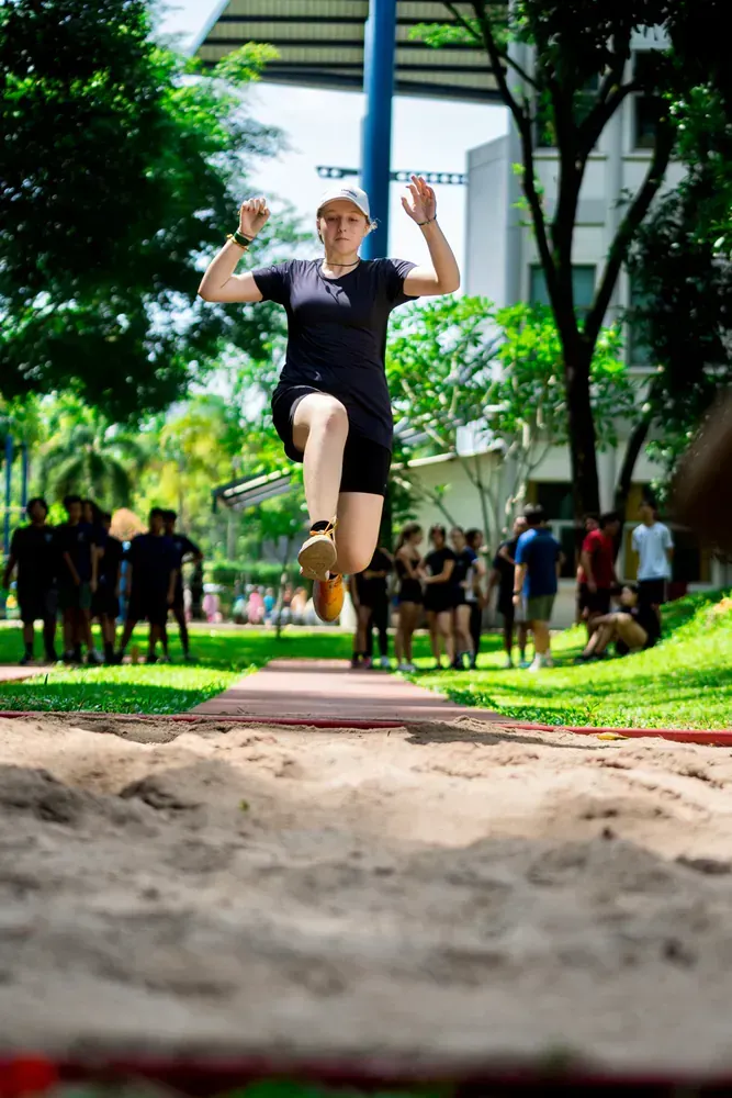 A woman is jumping in the air while a group of people watch.