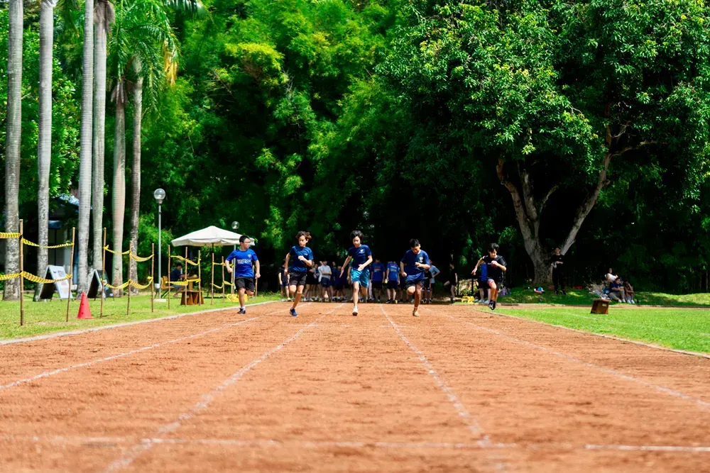 A group of people are running on a dirt track in a park.