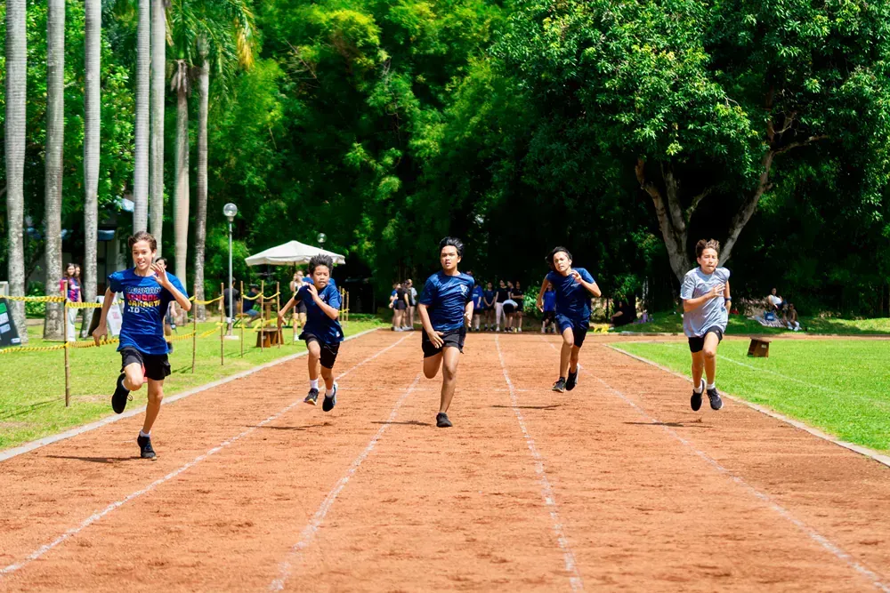 A group of children are running on a track in a park.