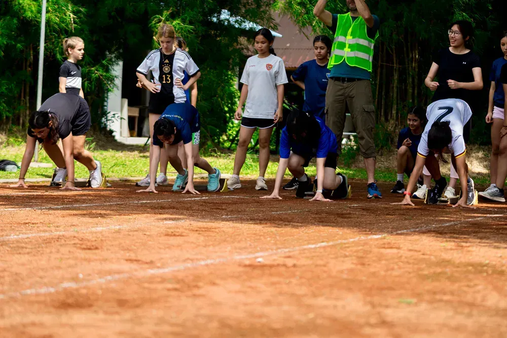 A group of people are getting ready to run on a dirt track.