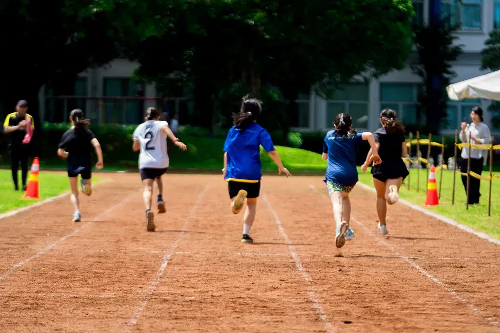 A group of young girls are running on a track.