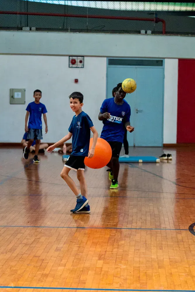 A group of young boys are playing a game of dodgeball in a gym.