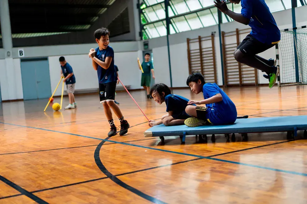 A group of young boys are playing a game of floorball in a gym.