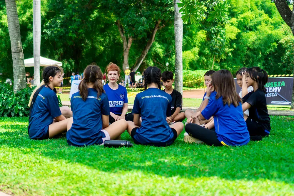 A group of children are sitting in a circle on the grass.