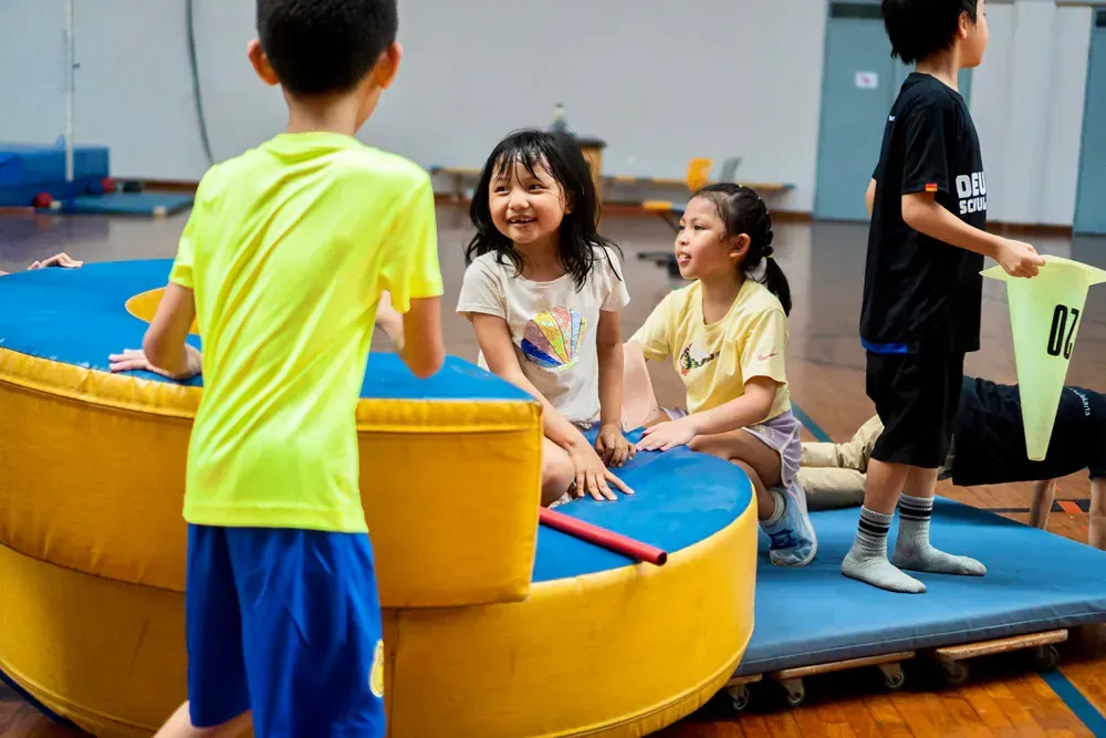 A group of children are playing on a trampoline in a gym.