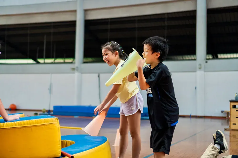 A boy and a girl are playing in a gym.