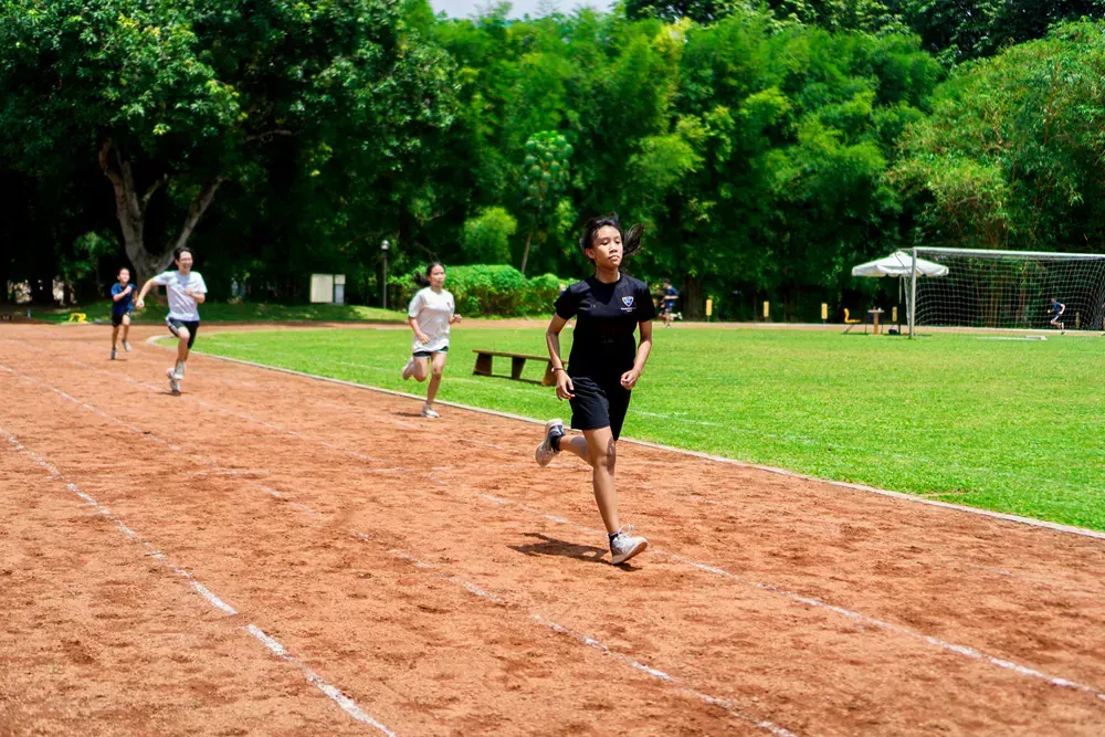 A group of people are running on a track in a park.
