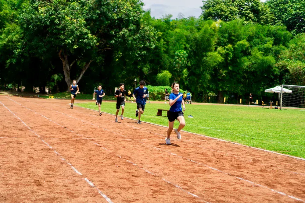 A group of people are running on a track in a park.