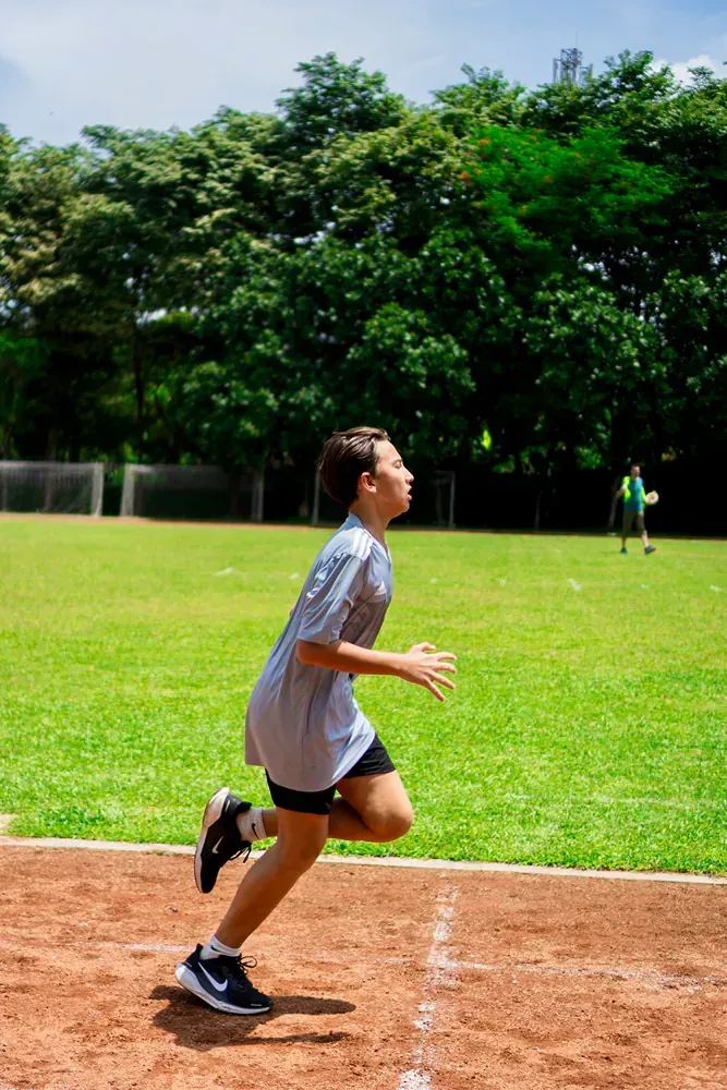 A young boy is running on a track in a field.