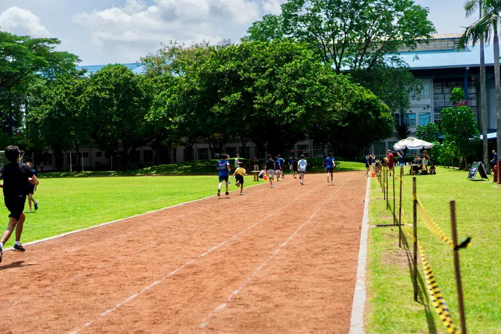 A group of people are running on a track in a park.