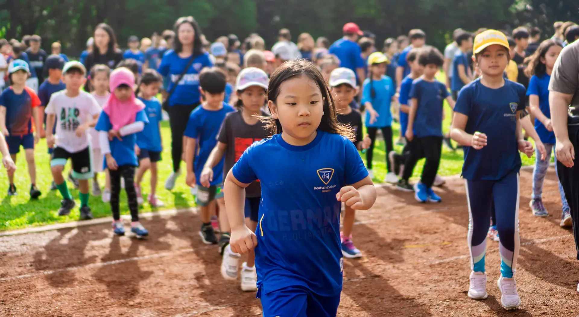 A group of children are running on a dirt track.