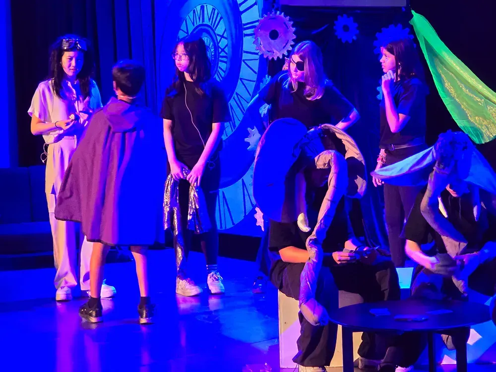 A group of people are standing on a stage in front of a clock.