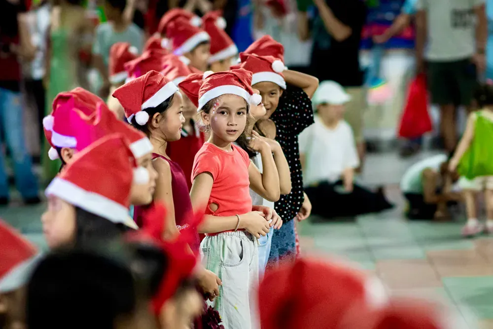 A group of children wearing santa hats are standing in a line.