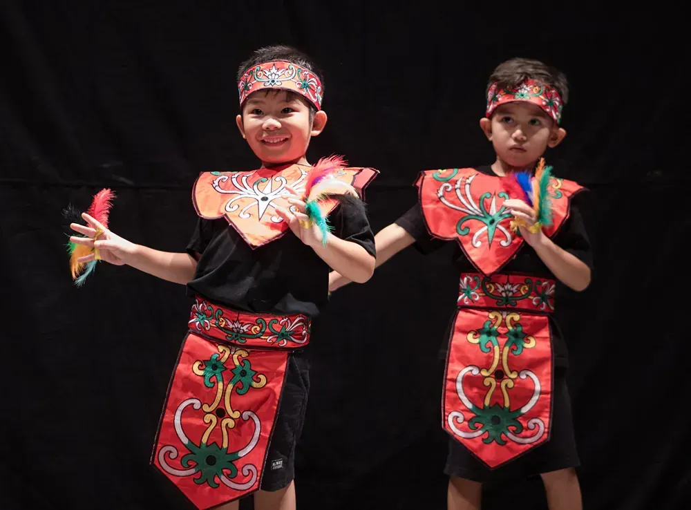 Two young boys in traditional costumes are standing next to each other on a stage.