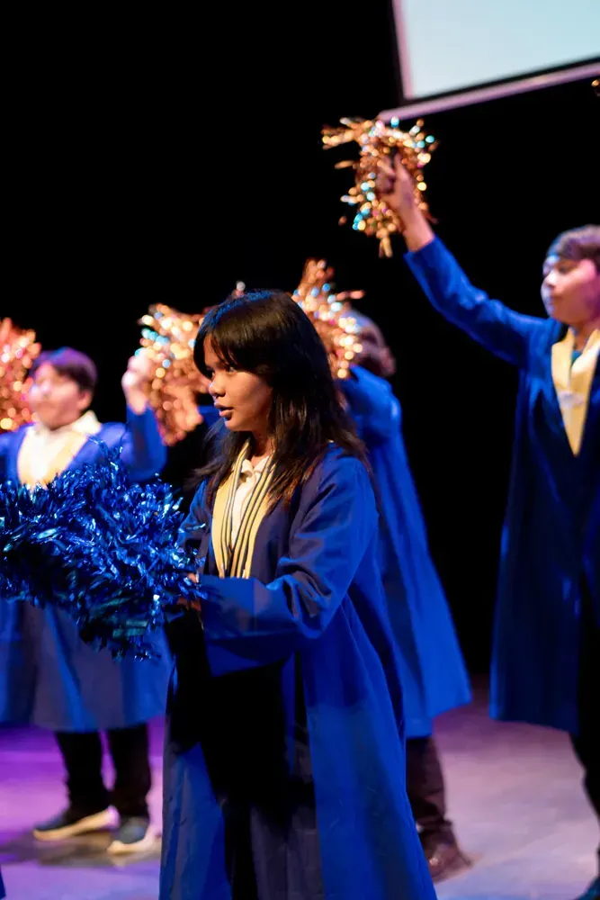 A group of people are standing on a stage holding pom poms.