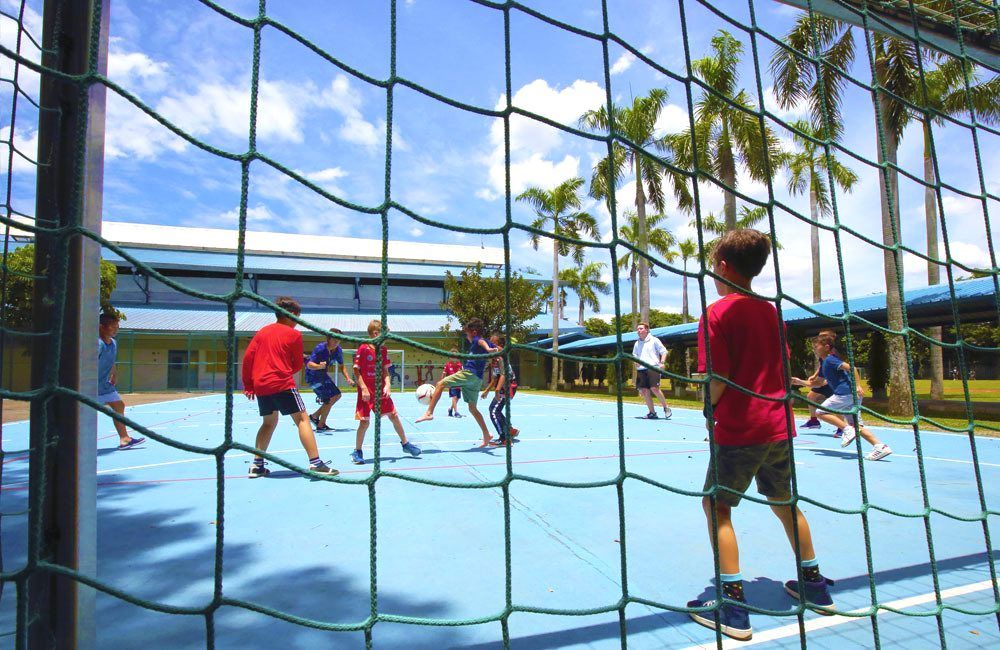 A group of children are playing volleyball on a court