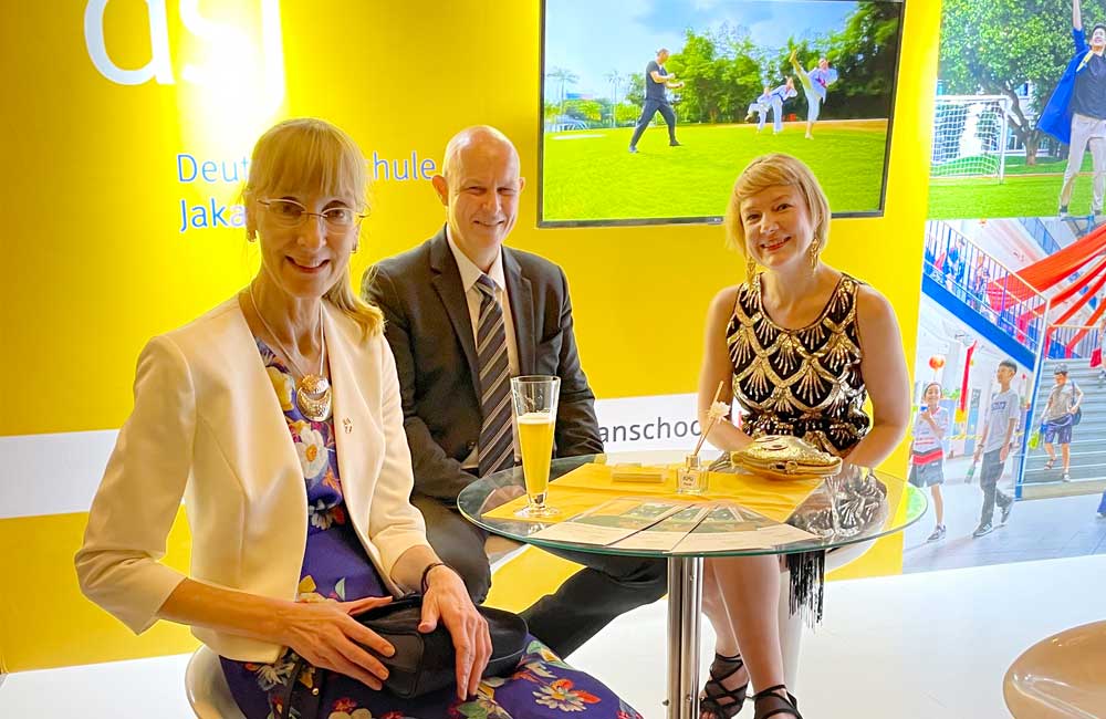 A group of people are sitting at a table in front of a yellow wall.