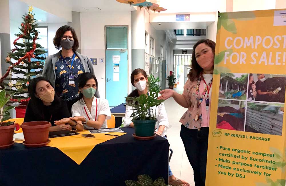A group of people wearing masks are standing around a table with potted plants.