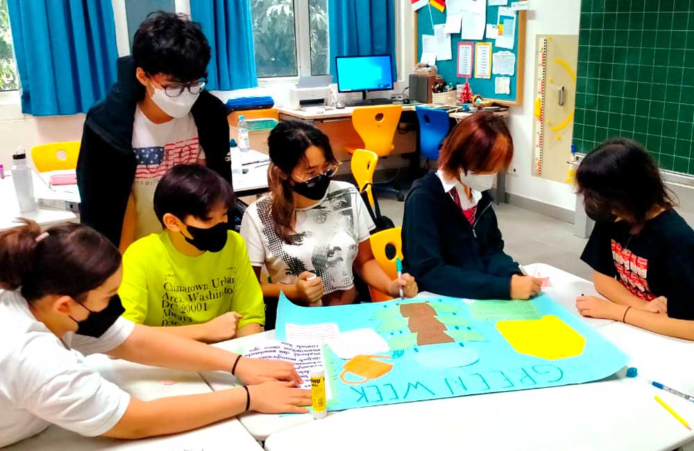 A group of children wearing face masks are sitting around a table in a classroom.