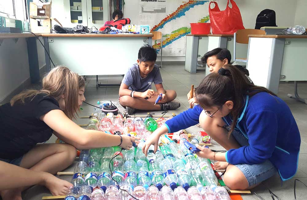 A group of children are sitting on the floor playing with plastic bottles.