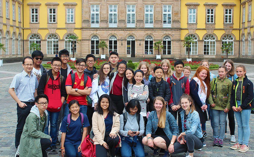 A group of young people are posing for a picture in front of a large building.