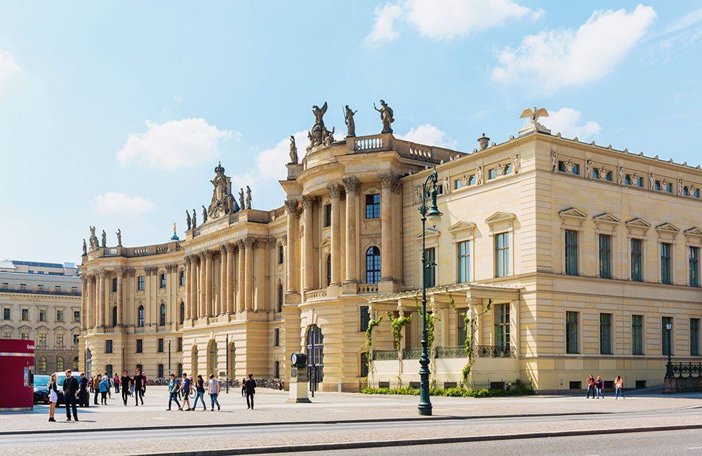 A group of people are walking in front of a large building.