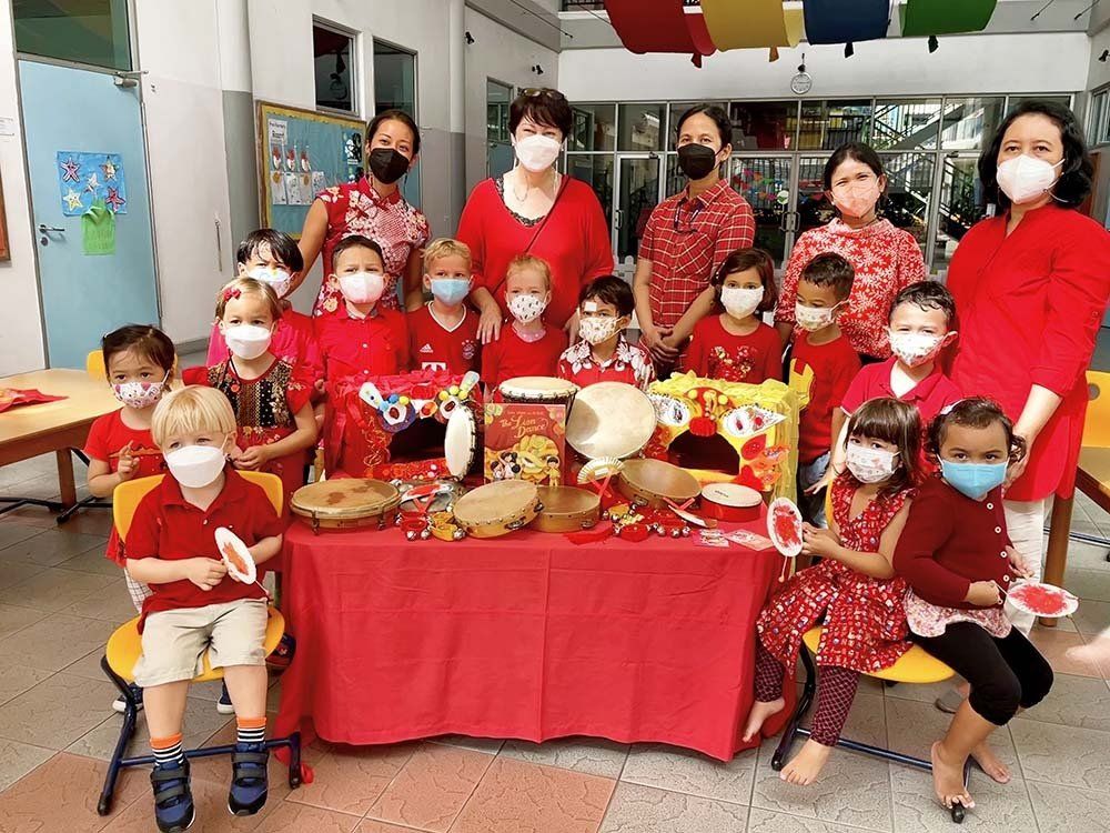 A group of children wearing face masks are standing around a table.