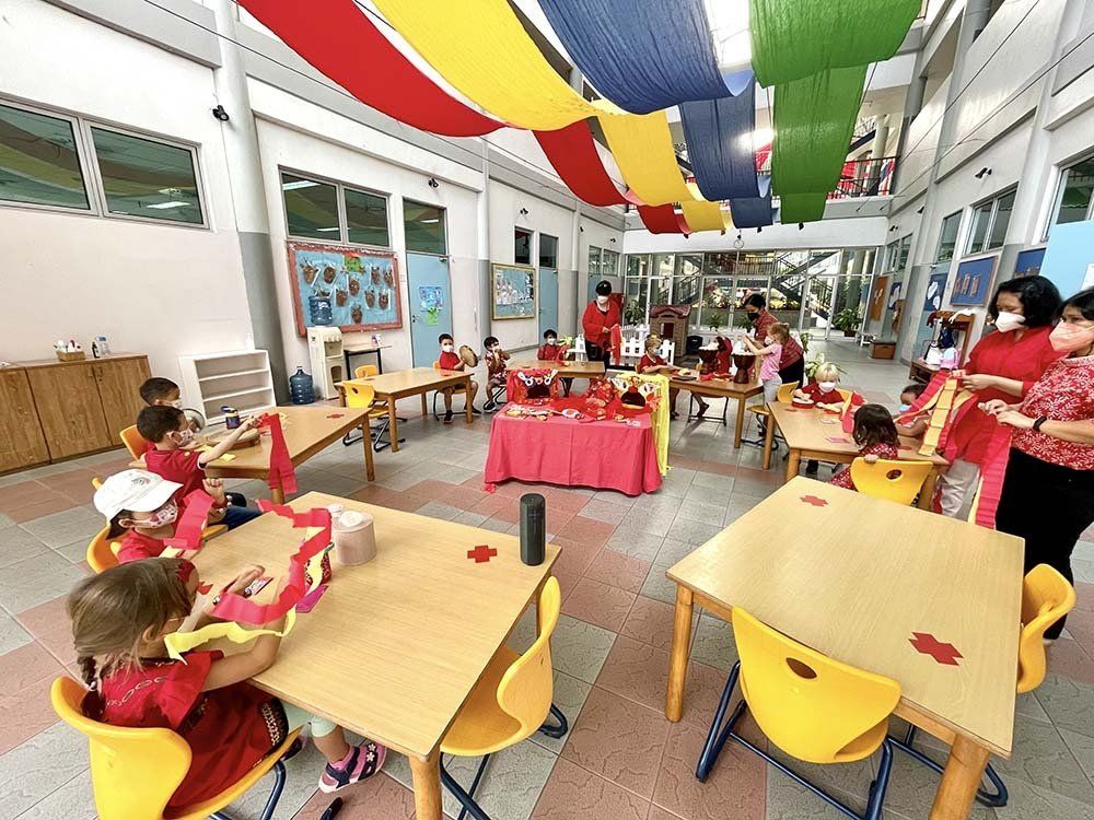 A group of children are sitting at tables in a classroom.
