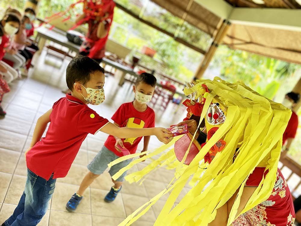A group of children wearing face masks are playing with a yellow decoration.