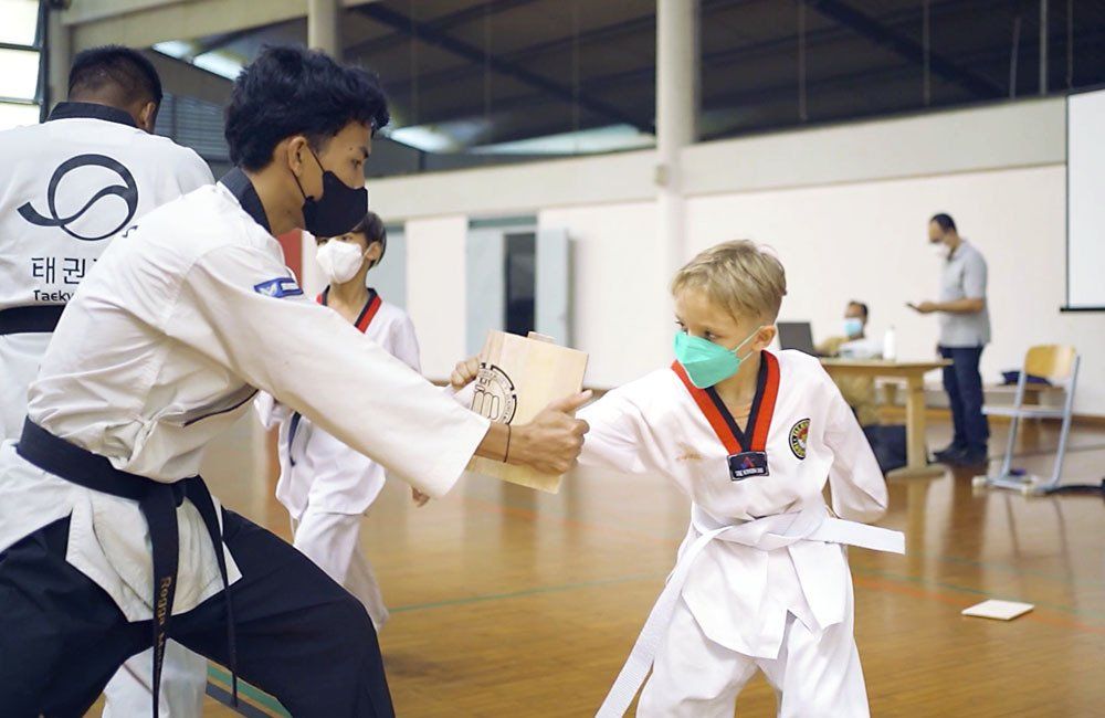 A man in a karate uniform is giving a certificate to a young boy.